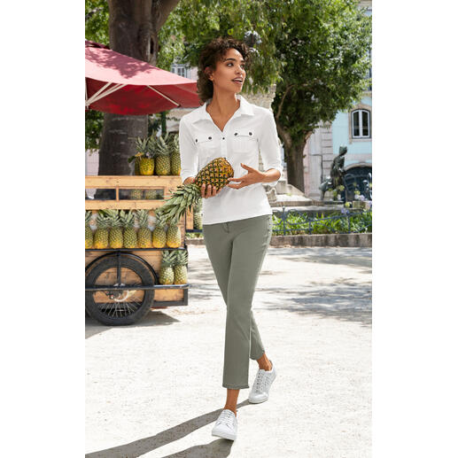 Kaki Femme en blouse blanche et pantalon vert tenant une ananas en marchant.