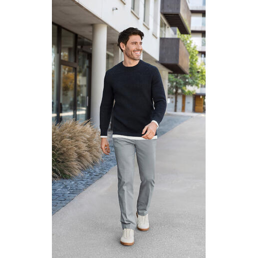 Pantalon chino Oxford Hiltl Homme en pull à gaufres noir et pantalon gris, marchant sur un trottoir moderne.