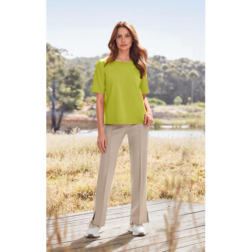Femme en haut vert et pantalon beige en tissu à la campagne.