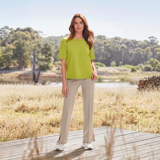 Femme en haut vert et pantalon beige en tissu à la campagne.