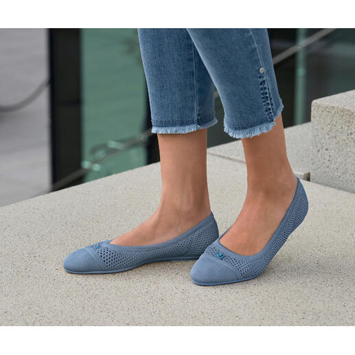 Femme portant des ballerines en mesh bleues, debout à l'extérieur sur un sol en pierre.