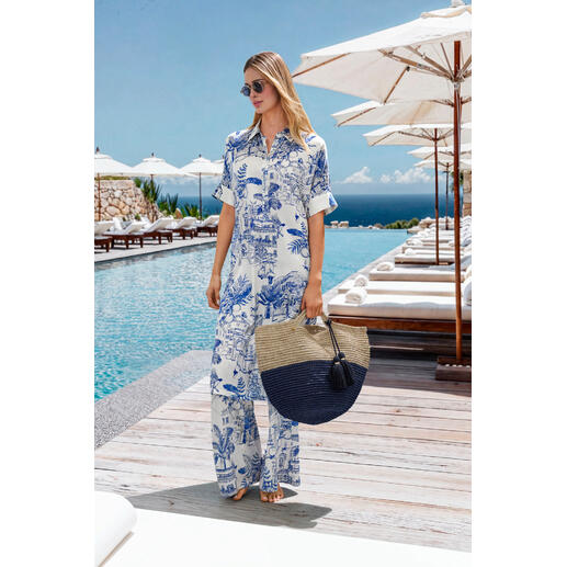 Femme en combinaison stretch de soie au bord de la piscine, tenant un grand sac, ciel bleu.