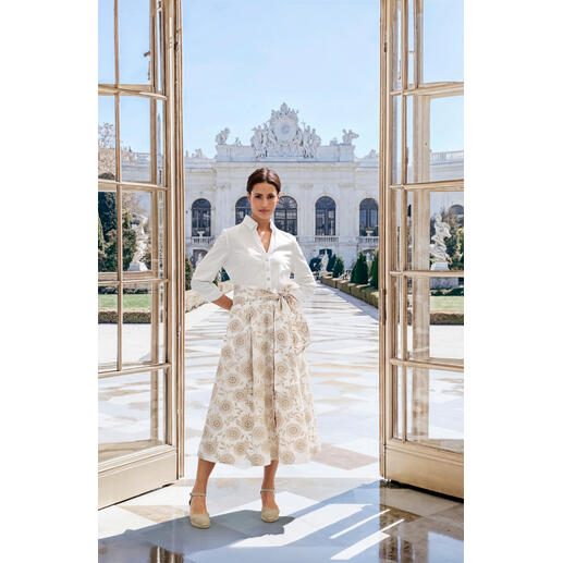 Robe-chemisier à broderie anglaise Steinbock Femme dans une robe-blouse brodée devant un bâtiment élégant.