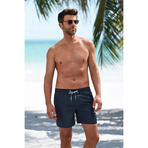 Shorts de bain à motif bleuet JOOP! Homme en shorts de bain JOOP! fleurs de bleuet se tient sur la plage.
