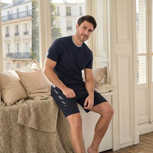 Homme assis dans une pièce portant un pyjama de récupération bleu marine à manches courtes.