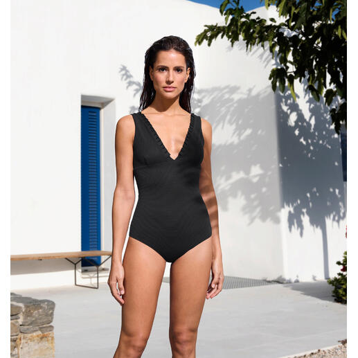Maillot de bain réversible en piqué Mymarini Femme portant un maillot de bain réversible en piqué noir devant un bâtiment moderne blanc.