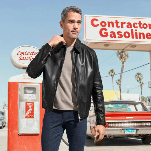 Homme en blouson soft en cuir de veau noir et pull beige devant une station-service.