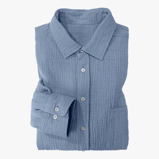 Chemise en mousseline bleu clair pliée, visible avec des boutons et une poche poitrine.