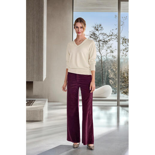 Crème Femme portant un pantalon large en velours côtelé bordeaux et un pull en V