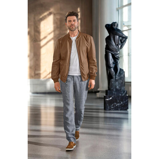 Blouson réversible métis OCONI Homme portant une veste réversible OCONI Metis marron, avec une statue en arrière-plan.