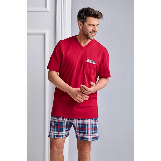 Homme portant un pyjama rouge avec un short à carreaux bleu et blanc.
