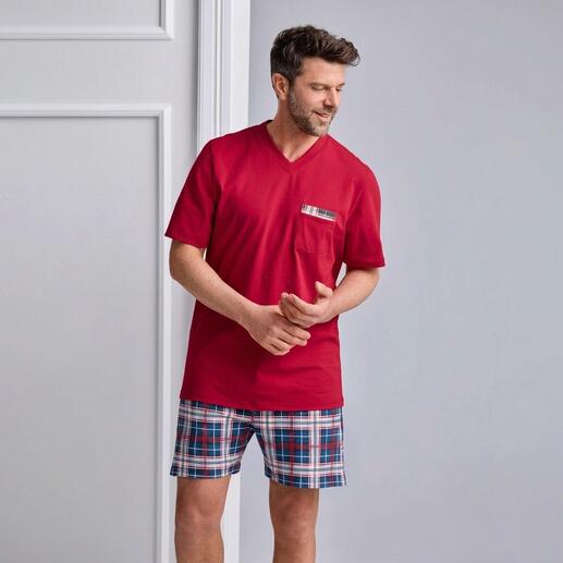 Homme portant un pyjama rouge avec un short à carreaux bleu et blanc.