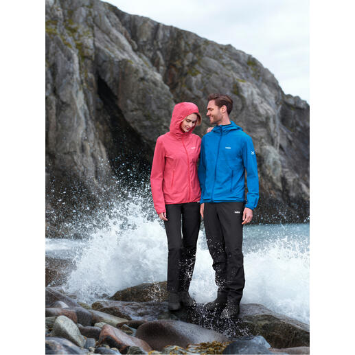 Couple en vêtements d'extérieur, une personne porte une veste softshell rose, l'autre en veste bleue à côté d'une eau agitée.