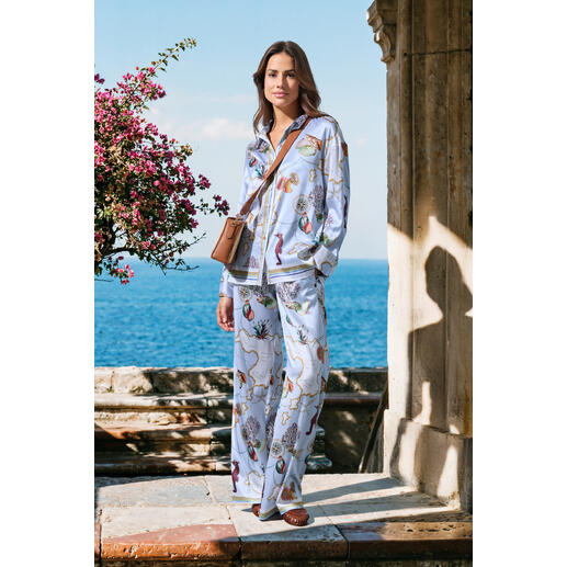 Femme en pyjama en soie avec motif floral coloré au bord de la mer.