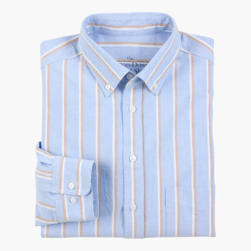 Chemise bleue avec des rayures blanches et brunes, pliée sur un fond blanc.