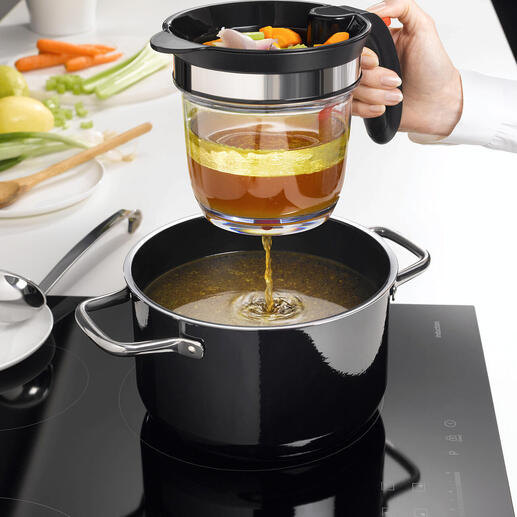 Main utilisant un tamis pour verser du bouillon de légumes dans une casserole, avec une cuisine en arrière-plan.