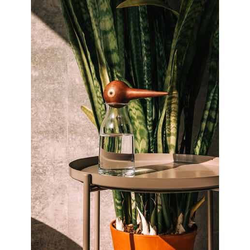 Vase en verre avec un distributeur d'eau en bois en forme d'oiseau sur une table.