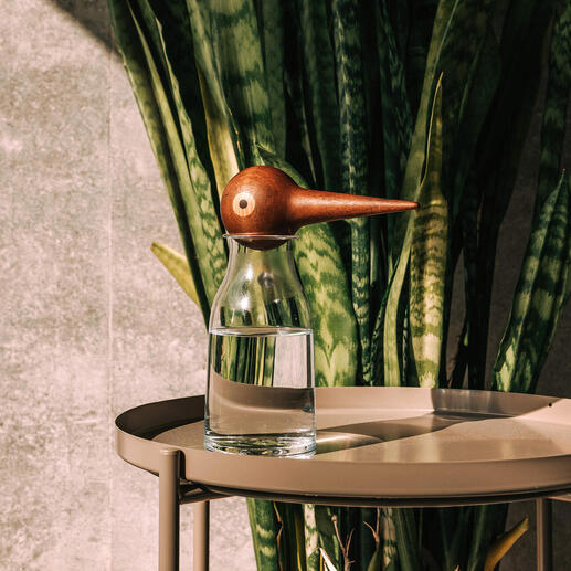 Vase en verre avec un distributeur d'eau en bois en forme d'oiseau sur une table.