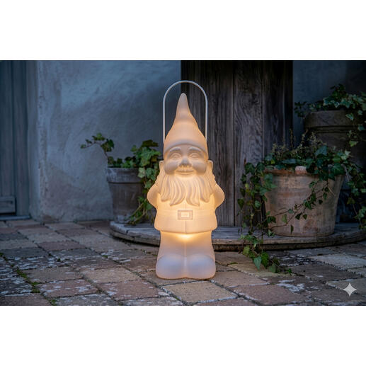 Gnome de jardin LED avec lumière douce, placé sur un sol en briques près de pots de fleurs.