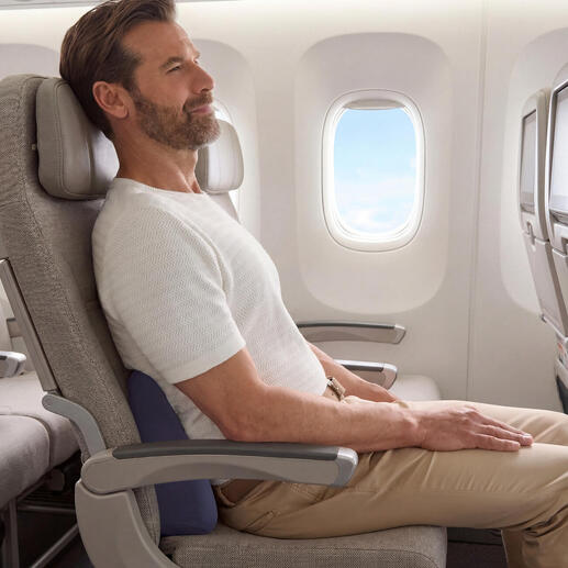 Homme assis dans un avion avec un coussin de voyage pour le soutien du dos.