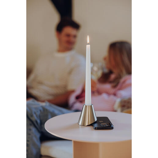 Bougie dans un support en métal sur une table, arrière-plan avec des personnes.
