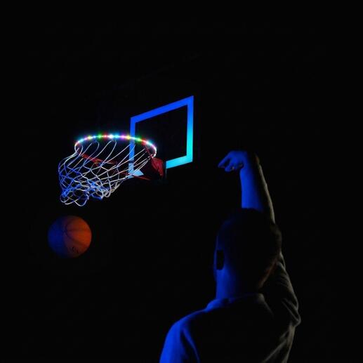Panier de basket-ball avec lumières LED colorées et personne lançant sur un terrain sombre.