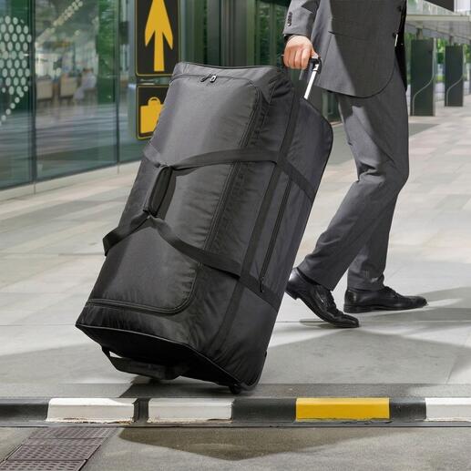 Un sac de voyage ultraléger XXL noir est poussé par un homme en costume.