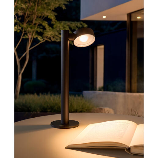 Lampe de table à batterie sur une table à l'extérieur, avec un livre à côté.