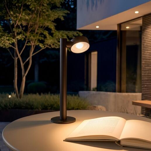 Lampe de table à batterie sur une table à l'extérieur, avec un livre à côté.