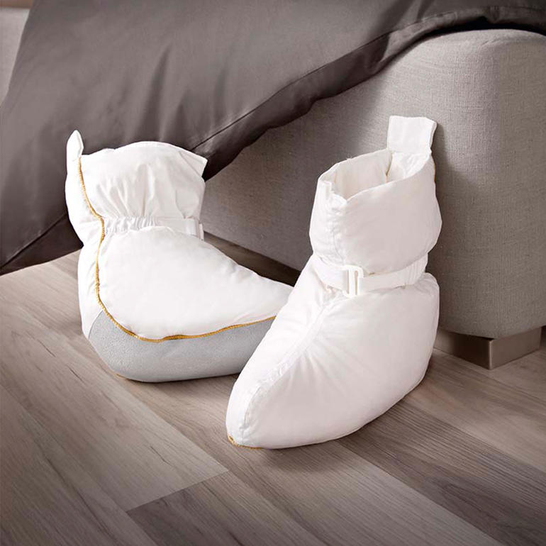 Chaussons de lit en matériau doux sur un sol en bois.