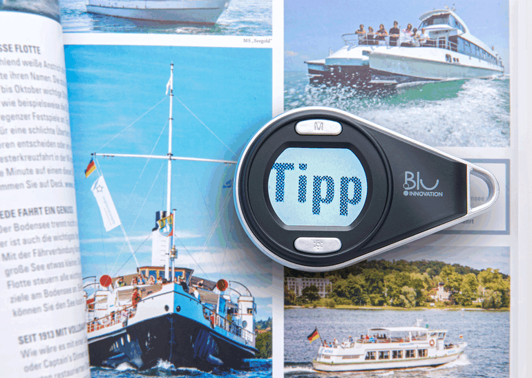 Loupe de poche numérique Loupe numérique sur un magazine ouvert avec des images de bateaux.