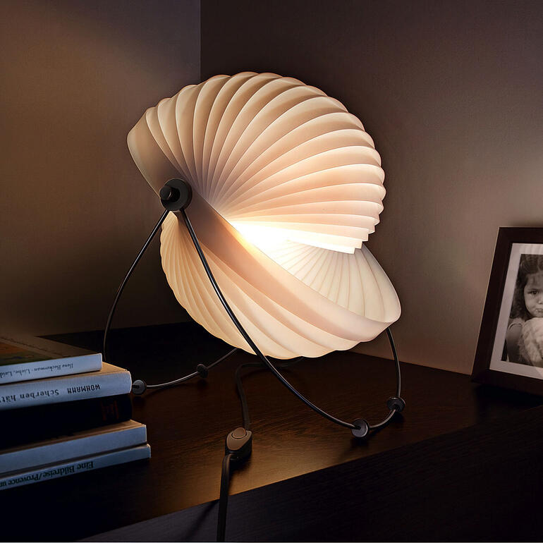Lampe design 'Eclipse' avec une lampe en forme de pétale sur une table.