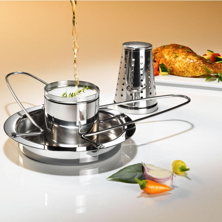 Le liquide s’évaporant de la rôtissoire de poulet garantit une viande tendre et juteuse. Grilleur de poulet avec embout aromatique en cours d'assaisonnement sur fond clair.