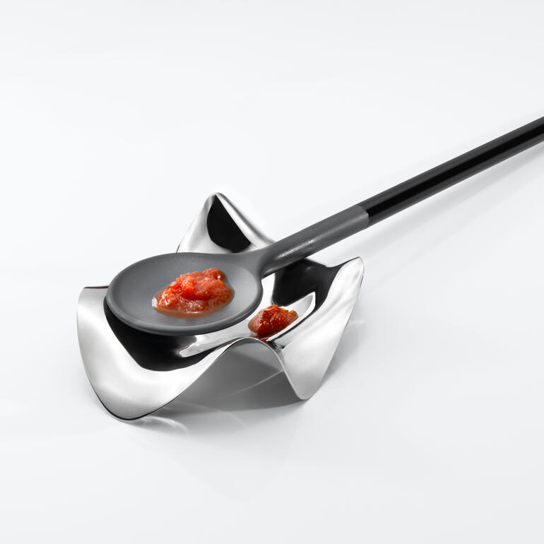 Repose-cuillère design par Alessi Support de cuillère moderne avec une cuillère noire et de la sauce.