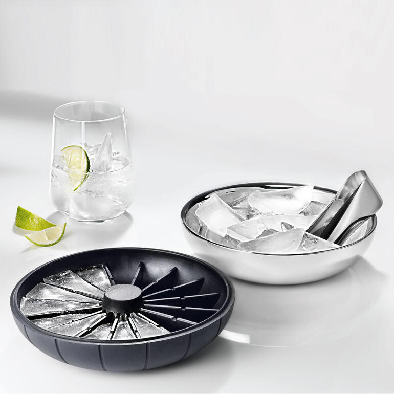 Le couvercle en silicone sert également de moule à glaçons. Fabricant de glaçons 3 en 1 avec couvercle, à côté d'un verre plein de glaçons.