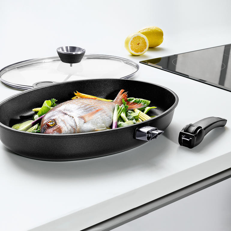 Poêle à poisson en aluminium coulé XXL avec du poisson et des légumes sur la cuisinière.