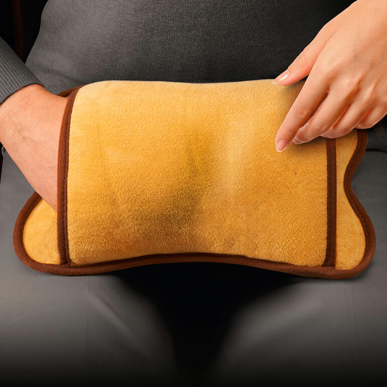 Bouillotte électrique avec une surface douce beiges dans la main.