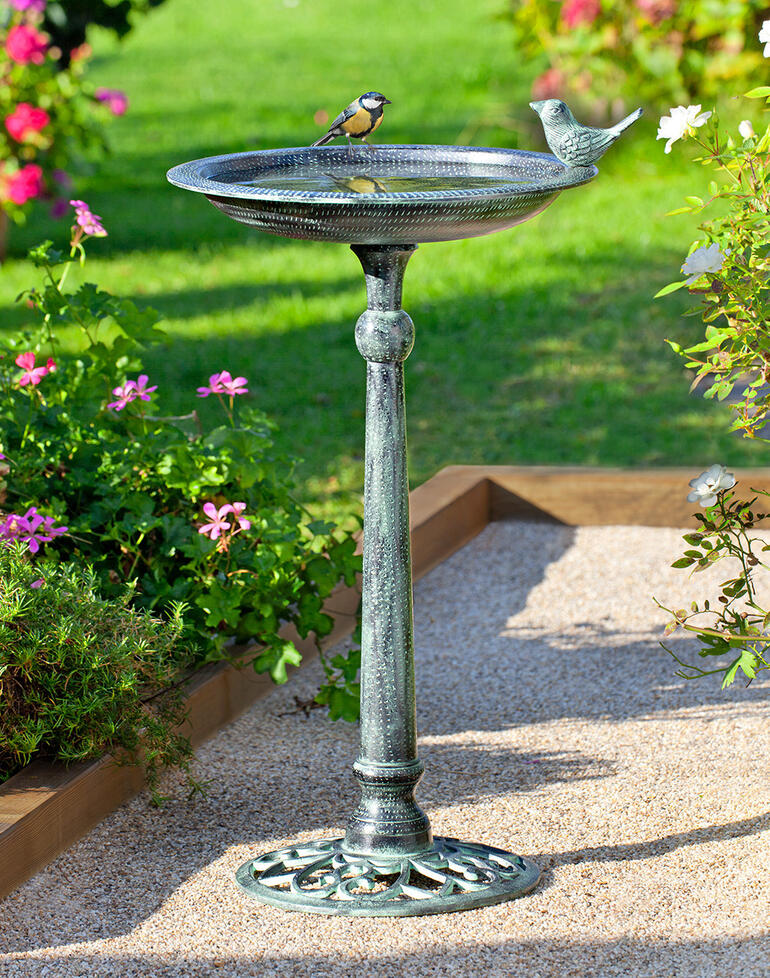 Bain d'oiseau victorien avec un oiseau dans un jardin en fleurs
