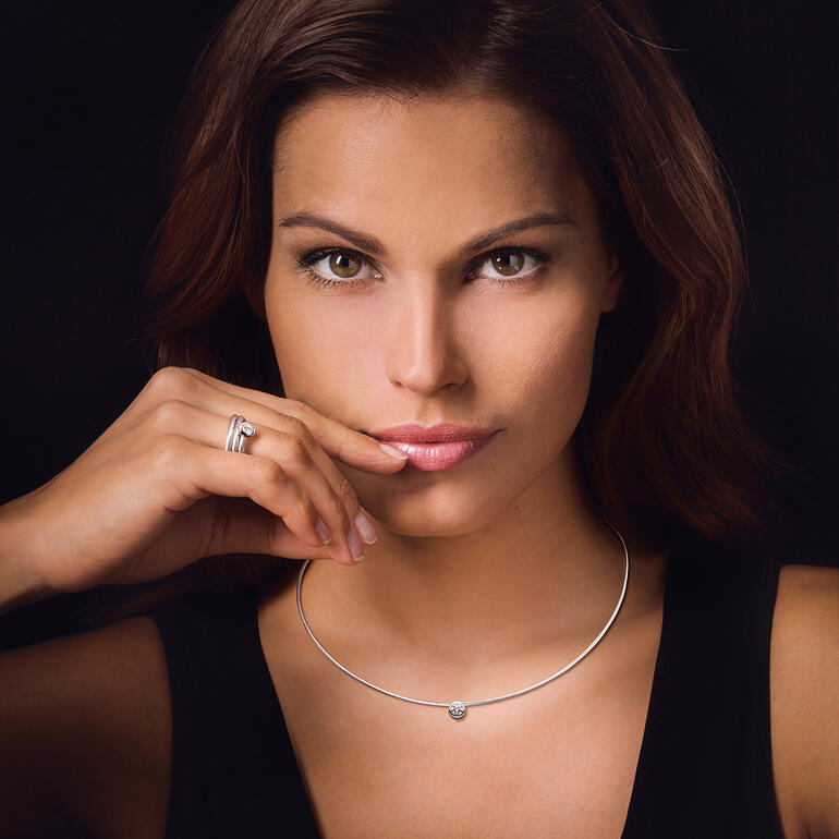 Femme portant une bague spirale en diamant et un collier en câble.
