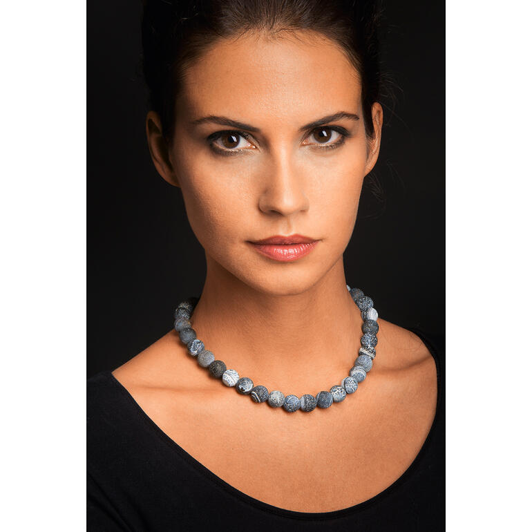 Les agates de couleur gris-bleu se marient parfaitement avec des tenues tant décontractées qu’élégantes. Femme portant un collier en agate avec différentes pierres bleues