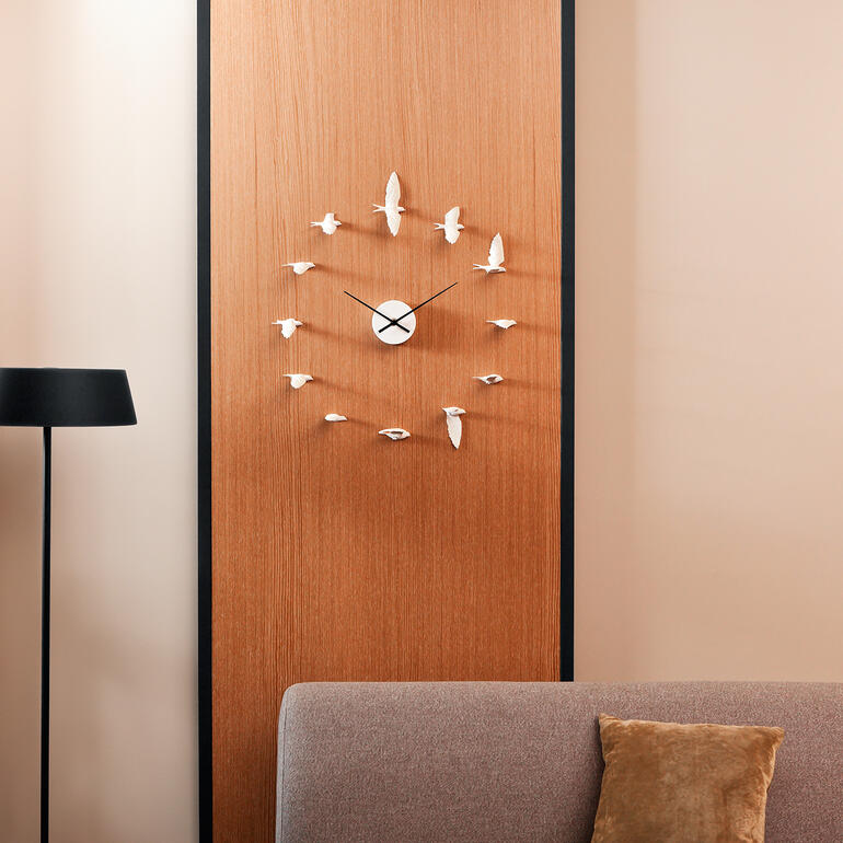 Horloge en forme d'hirondelle sur un mur en bois au-dessus d'un canapé.