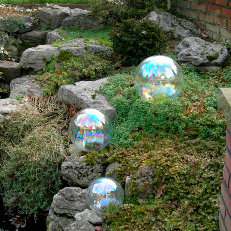 Trois grandes bulles de savon sur de la mousse verte entre des pierres