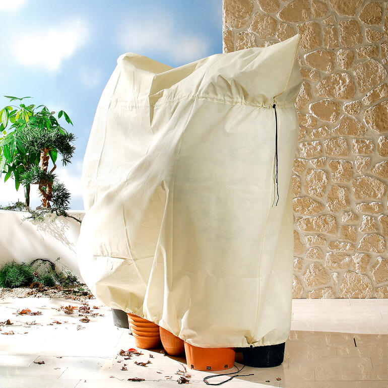 Housse de protection pour plantes en matériau beige.