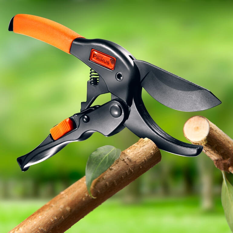 Ciseaux à glissement Primus avec poignée ergonomique dans un jardin.