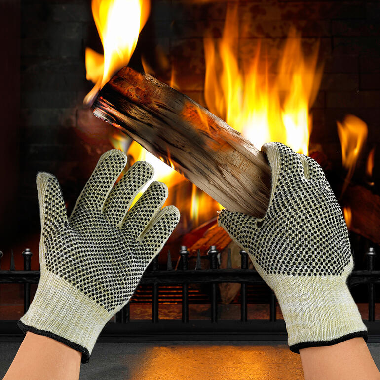 Gants de protection contre la chaleur Gants de protection thermique tenant un morceau de bois devant un feu.