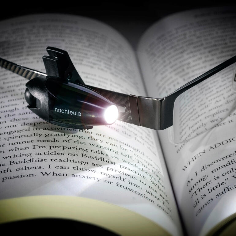 Lampe clip avec une lumière LED intégrée sur un livre ouvert.