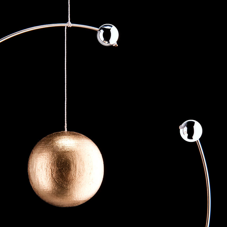 Mobile modèle atomique de Niels Bohr Gros plan d'une balle dorée dans le modèle atomique, entourée d'électrons argentés.