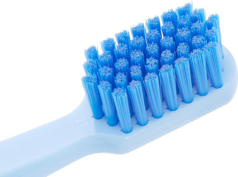 Gros plan d'une tête de brosse à dents blanche avec des poils bleus.