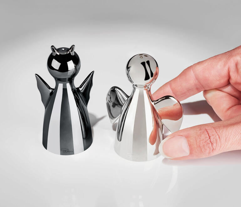 Deux salières, une noire et une argentée, dans la main d'une personne.