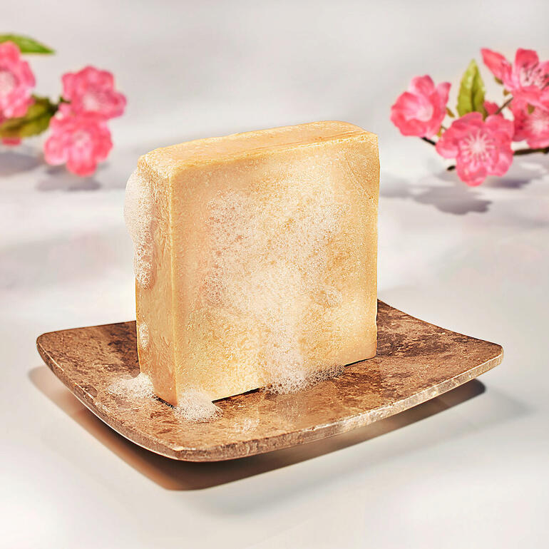 Savon au lait de peau avec des fleurs sur un plateau décoratif.